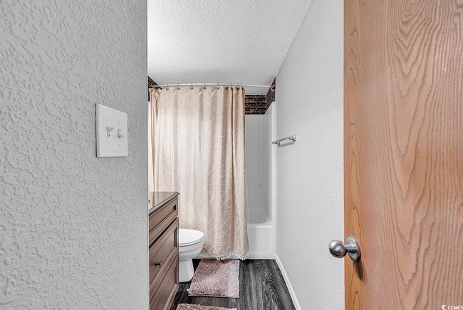 Full bathroom with shower / bathtub combination with curtain, vanity, toilet, a textured wall, and a textured ceiling | Image 6