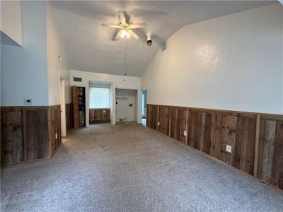 Unfurnished living room with a textured ceiling, high vaulted ceiling, ceiling fan, and carpet | Image 2