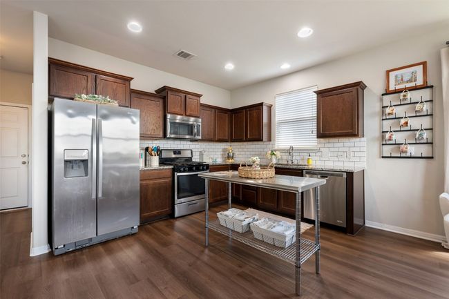 Kitchen featuring appliances with stainless steel finishes, dark brown cabinetry and backsplash. | Image 9