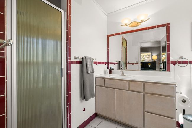 Bathroom with tile walls, ornamental molding, a shower with shower door, vanity, and tile patterned floors | Image 21