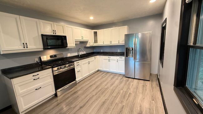 Stainless appliances, shaker cabinets, open concept to living | Image 9