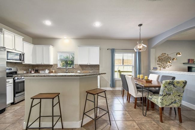 Tile flooring, a large center island/bar, and granite countertops grace the kitchen. | Image 11
