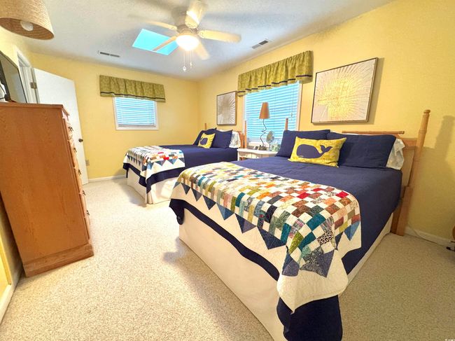 Bedroom featuring light colored carpet, ceiling fan, and a skylight | Image 29