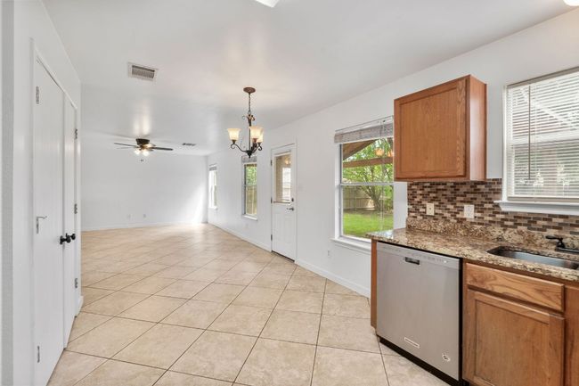Kitchen featuring stainless steel dishwasher, a sink, light tile patterned floors, brown cabinets | Image 16