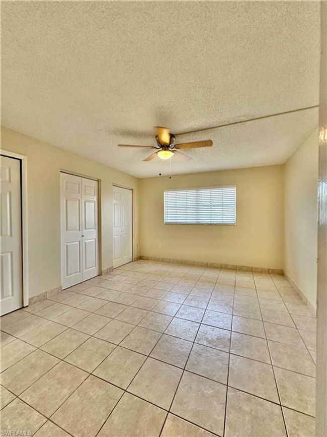 Unfurnished bedroom featuring two closets, light tile patterned flooring, a textured ceiling, and a ceiling fan | Image 10