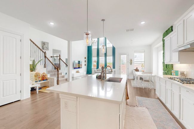 Kitchen with visible vents, a sink, light countertops, light wood-type flooring, and stainless steel gas cooktop | Image 11