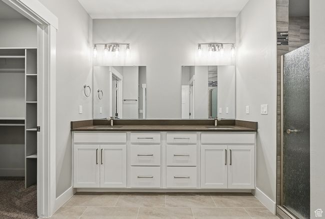 Full bathroom featuring double vanity, a shower stall, baseboards, and a walk in closet | Image 28