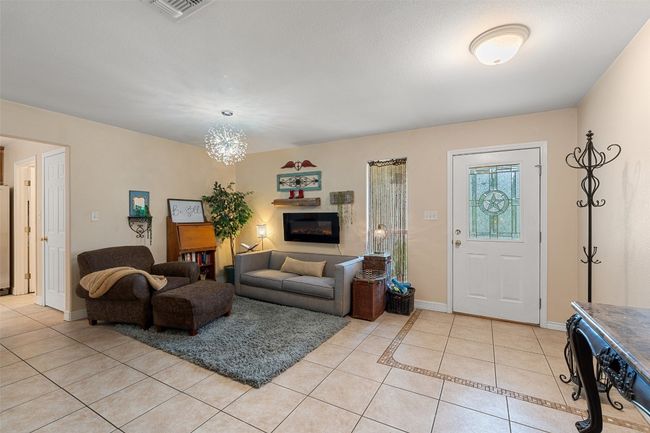 Living room with light tile patterned flooring, a glass covered fireplace, and baseboards | Image 8