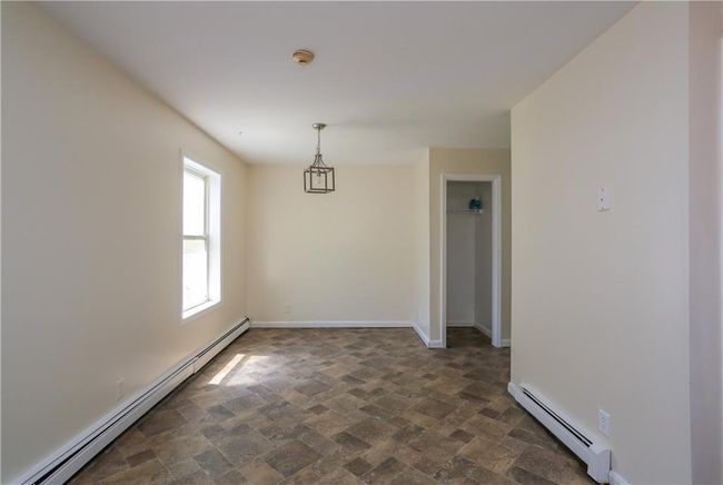Unfurnished room with a baseboard heating unit, a smoke detector, baseboards, and dark stone finish floors | Image 6