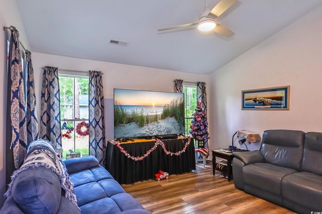 Living area featuring lofted ceiling, wood finished floors, a ceiling fan, and healthy amount of natural light | Image 4