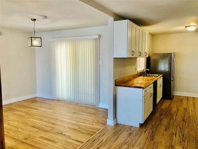 Kitchen featuring butcher block countertops, wood finished floors, white cabinetry, and black dishwasher | Image 7