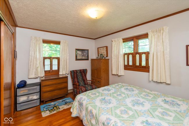 bedroom with wood finished floors, crown molding, a textured ceiling, and a closet | Image 17