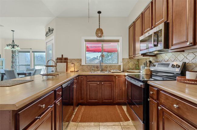 Kitchen with appliances with stainless steel finishes, a sink, a peninsula, and plenty of natural light | Image 9