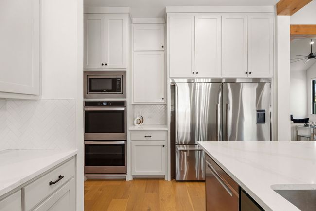 Kitchen with light wood-type flooring, white cabinets, and appliances with stainless steel finishes | Image 11