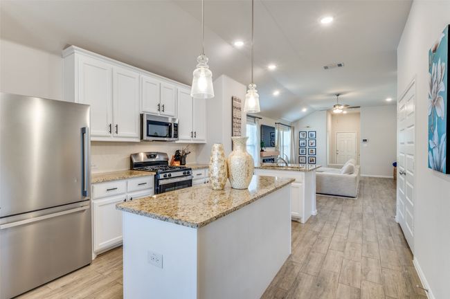 Kitchen featuring ceiling fan, visible vents, a center island, stainless steel appliances, and open floor plan | Image 9