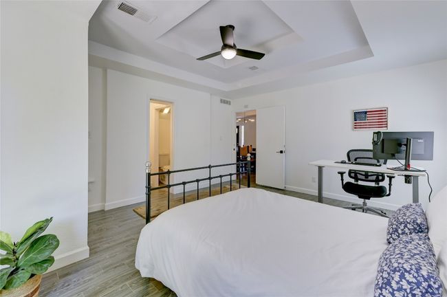 Bedroom featuring baseboards, visible vents, a tray ceiling, ceiling fan, and wood finished floors | Image 7