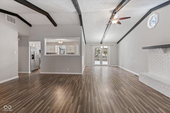 unfurnished living room featuring ceiling fan, dark wood-type flooring, a chandelier, and a textured ceiling | Image 4