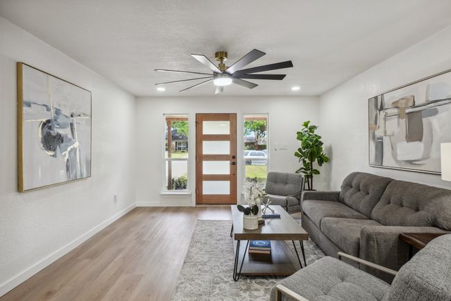 Living room with wood finished floors, baseboards, and a ceiling fan | Image 4