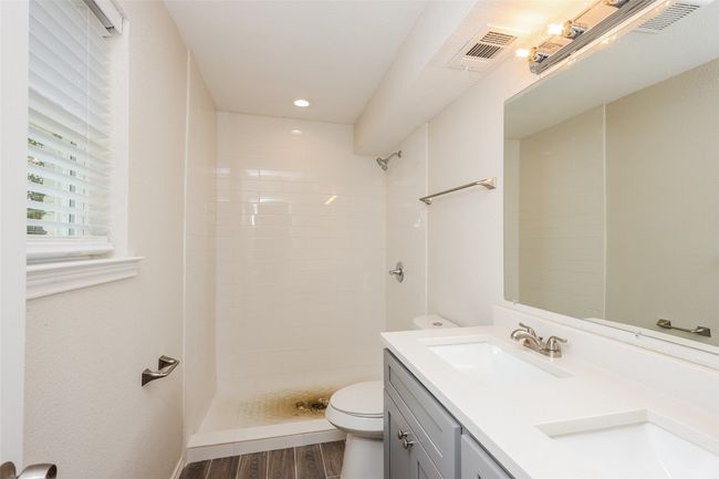 Full bathroom featuring wood finished floors, double vanity, a tile shower, and recessed lighting | Image 16