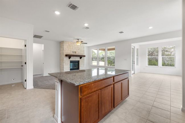 Kitchen with open floor plan, ceiling fan, light tile patterned floors, a fireplace, and recessed lighting | Image 5