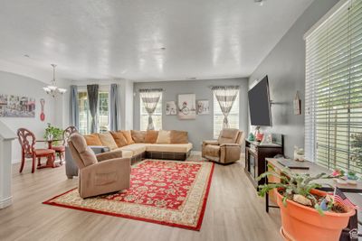 Living room with an inviting chandelier, light wood-type flooring, and a textured ceiling | Image 3