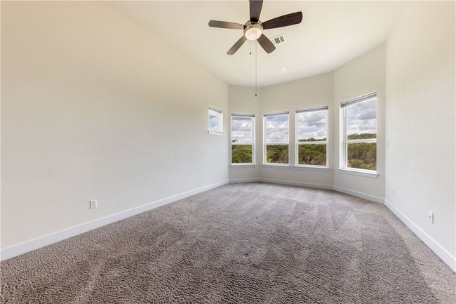 Primary suite with high ceilings and picture windows allowing natural light and hill country views. | Image 10