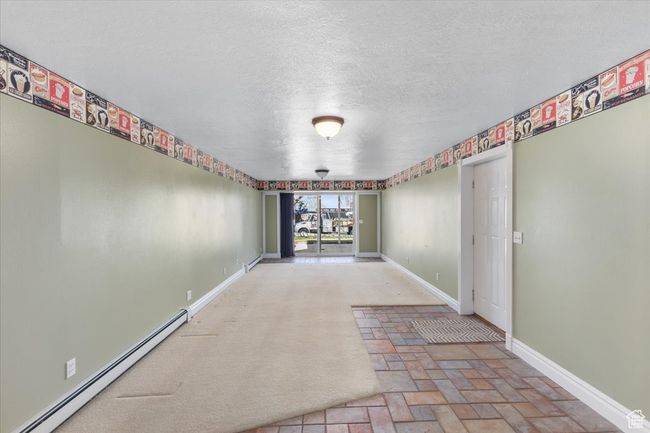 Hallway featuring a baseboard radiator, baseboards, stone finish flooring, and a textured ceiling | Image 25