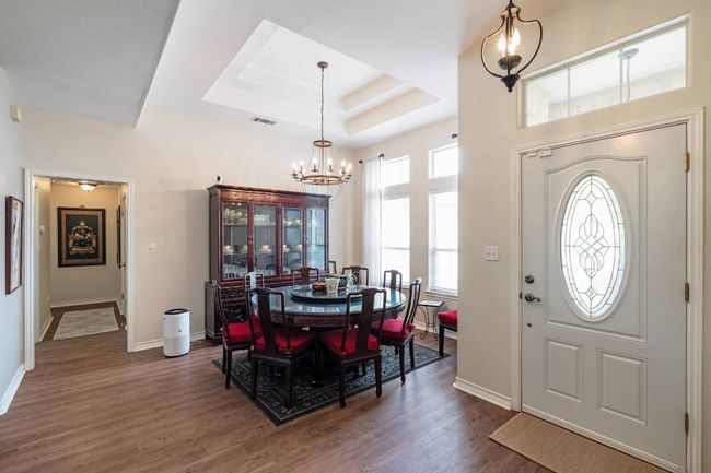 Foyer entrance with an inviting chandelier, a tray ceiling, baseboards, dark wood-style flooring, and visible vents | Image 17