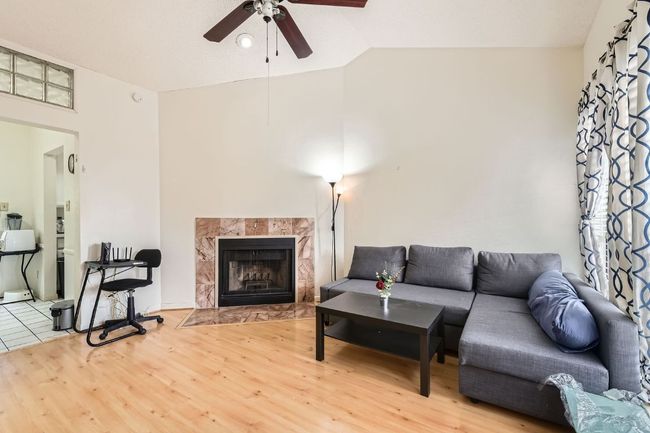 Living room with a fireplace, wood finished floors, ceiling fan, and vaulted ceiling | Image 7