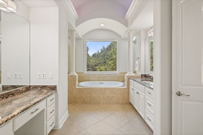 Full bathroom featuring decorative columns, two vanities, tile patterned flooring, a garden tub, and crown molding | Image 19