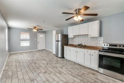 Kitchen with white cabinets, tasteful backsplash, light hardwood / wood-style flooring, sink, and stainless steel appliances | Image 3