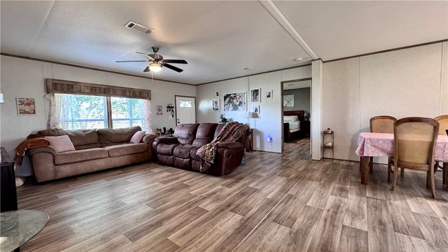 Living area with ceiling fan, ornamental molding, light wood-style floors, and a textured ceiling | Image 13
