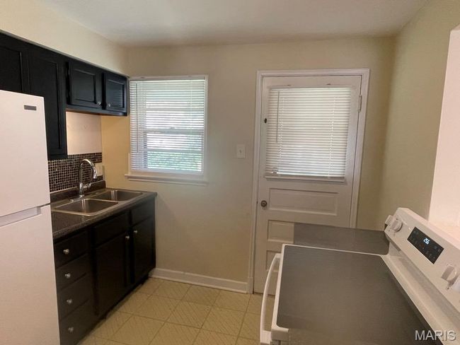 Kitchen with a sink, baseboards, freestanding refrigerator, dark cabinetry, and washer / clothes dryer | Image 10