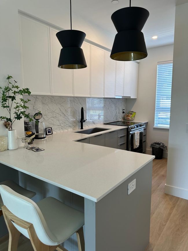 Kitchen featuring light wood-type flooring, range with electric cooktop, light countertops, and a sink | Image 8