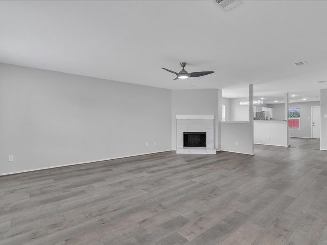 Unfurnished living room with wood finished floors, a ceiling fan, a fireplace, and baseboards | Image 6