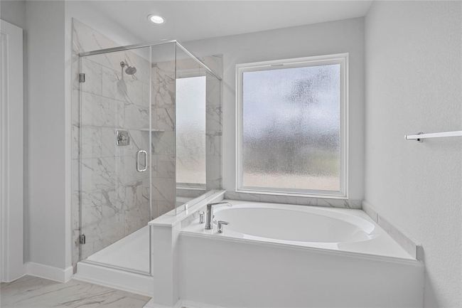 Additional view of the primary bathroom features walk-in shower with tile surround and separate garden tub. | Image 10