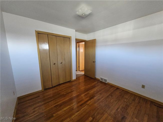 Unfurnished bedroom with baseboards, wood finished floors, visible vents, and a closet | Image 5