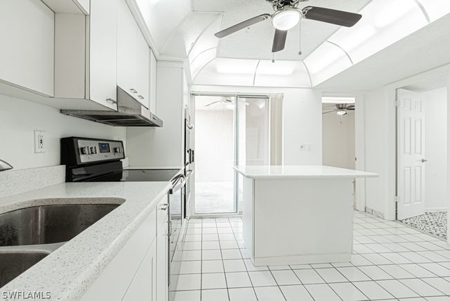 Kitchen with ceiling fan, stainless steel range oven, light tile floors, sink, and white cabinetry | Image 13