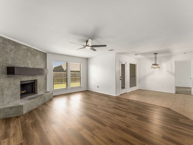 Unfurnished living room with a ceiling fan, wood finished floors, and a fireplace | Image 10