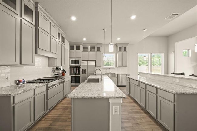 Featuring expansive granite countertops, double ovens, and sleek gray cabinetry with elegant crown molding | Image 8