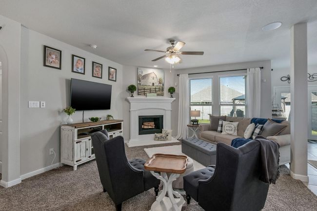 Living area featuring ceiling fan, carpet, a fireplace with raised hearth, and baseboards | Image 9