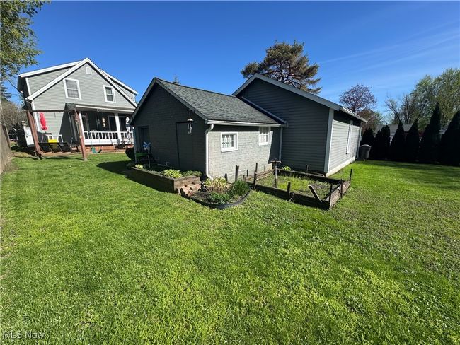 View of home's exterior featuring a lawn, roof with shingles, and a garden | Image 4