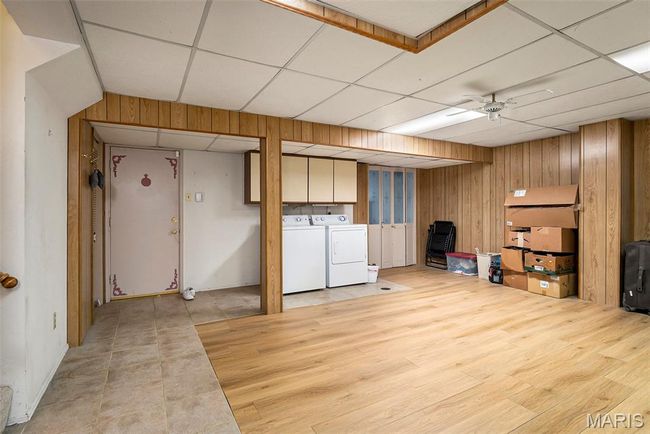 Finished below grade area featuring washer and clothes dryer, wood walls, a paneled ceiling, and light wood-type flooring | Image 19