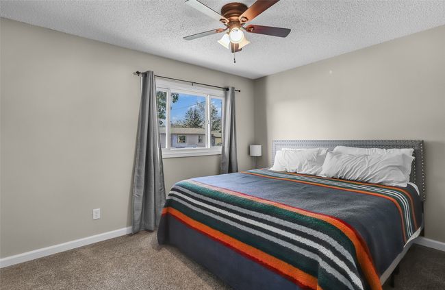 Carpeted bedroom featuring a textured ceiling, baseboards, and ceiling fan | Image 18