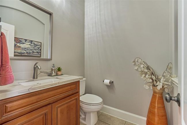 Elegant half bath featuring a sleek natural stone countertop. | Image 7