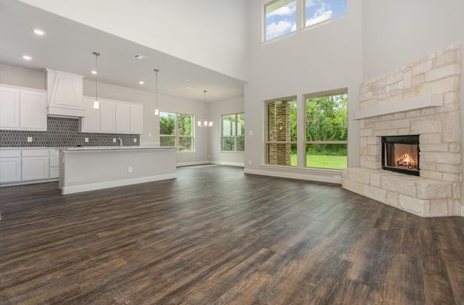 Unfurnished living room with a stone fireplace, dark wood finished floors, a chandelier, a high ceiling, and recessed lighting | Image 7