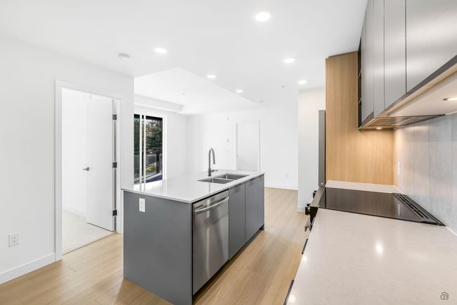 Kitchen with a kitchen island with sink, light wood finished floors, dishwasher, and a sink | Image 7