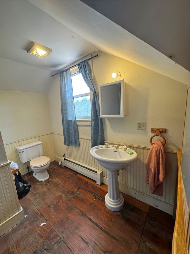 Half bathroom with toilet, wainscoting, lofted ceiling, baseboard heating, and hardwood / wood-style floors | Image 27