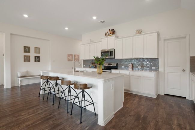 Kitchen featuring electric range oven, stainless steel microwave, a sink, backsplash, and dark wood-style floors | Image 6