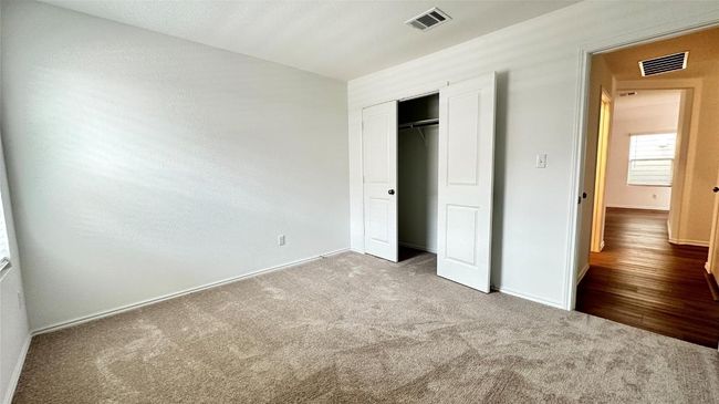 Unfurnished bedroom with carpet flooring, baseboards, visible vents, and a closet | Image 12